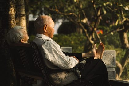 A peaceful older couple resting on a bench in a sunny garden