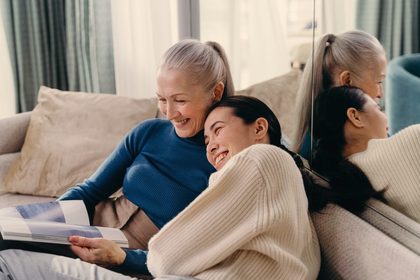 An older woman and a younger woman laughing together at home